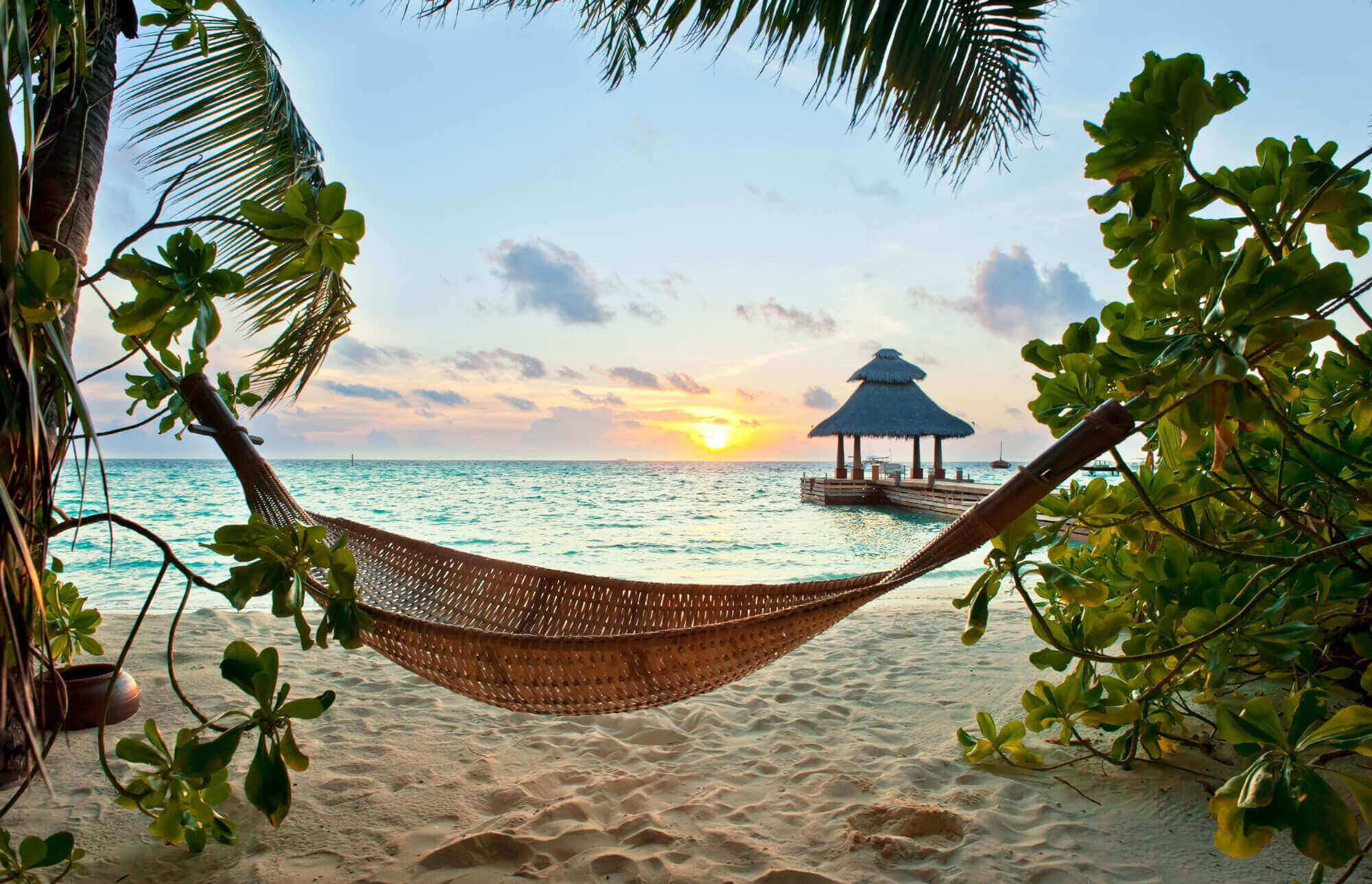 Malediven Urlaub-Haengematte am Strand bei Sonnenaufgang über dem Meer